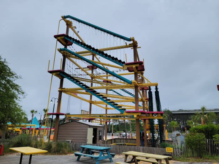 Three story ropes course with picnic tables below it