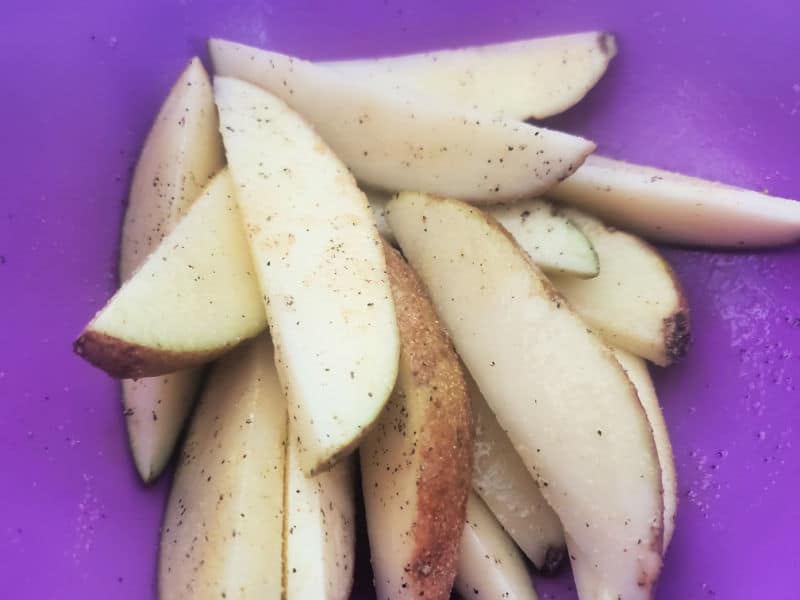 potato wedges with seasoning in a purple bowl 