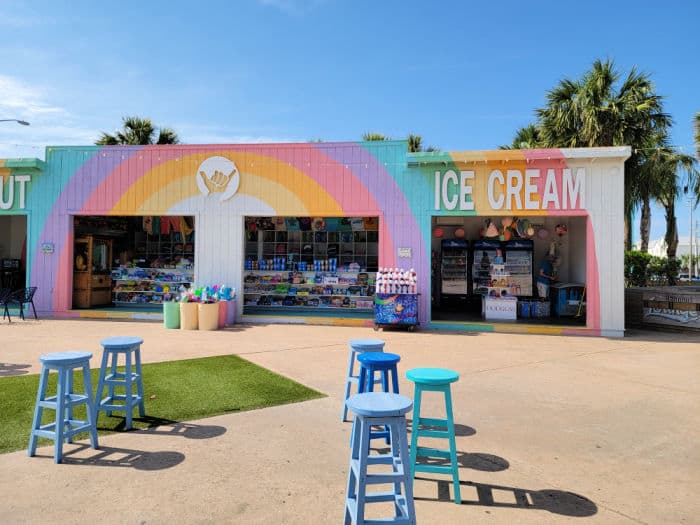 Rainbow building with an ice cream sign next to blue stools 