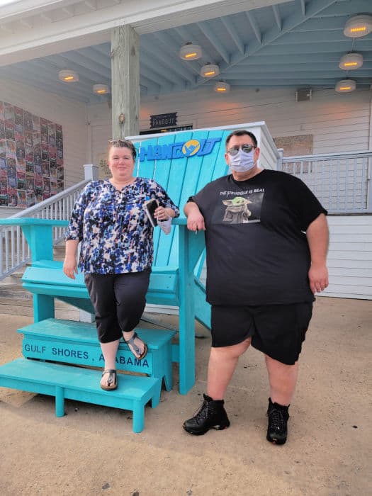 Tammilee and John next to the large blue Adirondack Chair at The Hangout