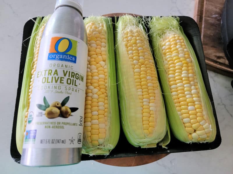 Olive oil spray sitting on corn on the cob 