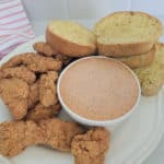 a white bowl filled with sauce, garlic bread, and chicken pieces