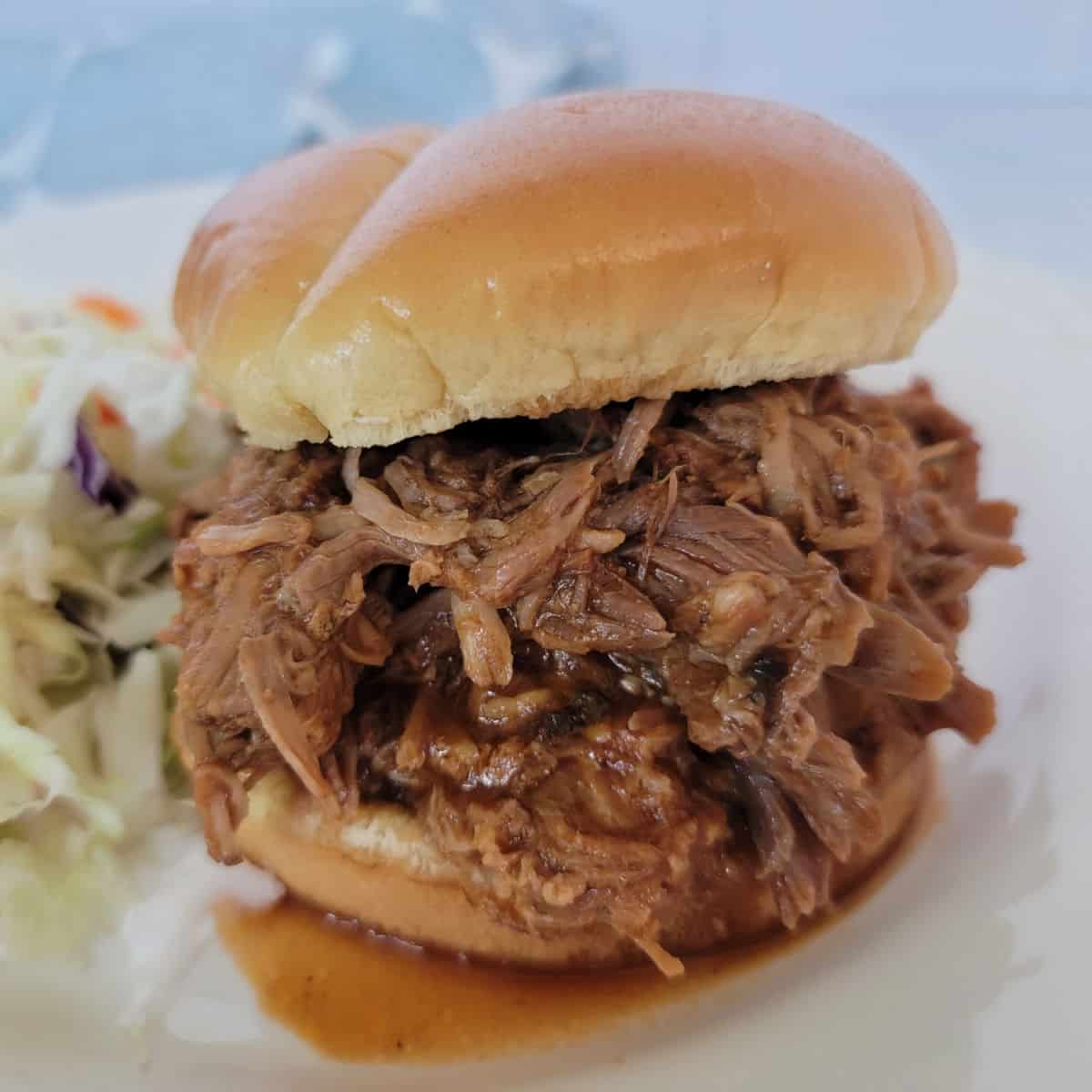 Dr Pepper Pulled pork piled on a sandwich bun next to coleslaw