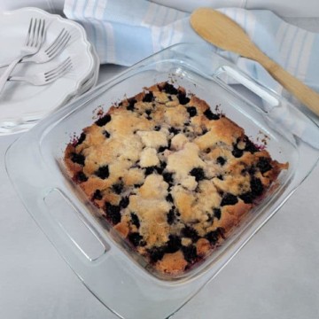Bisquick Blackberry Cobbler in a glass dish next to a wooden spoon