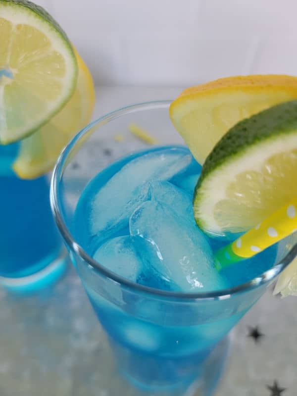 Close up of an electric lemonade blue cocktail with lemon and lime garnish