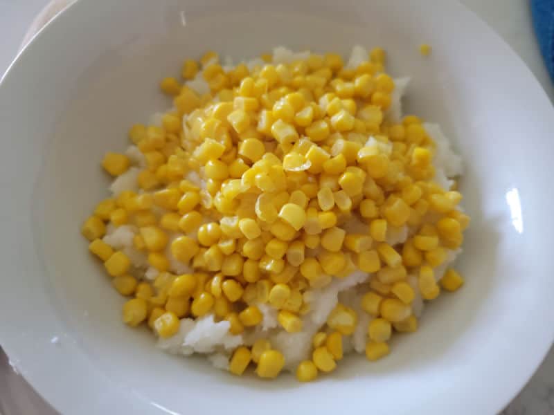 Corn on top of mashed potatoes in a white bowl 