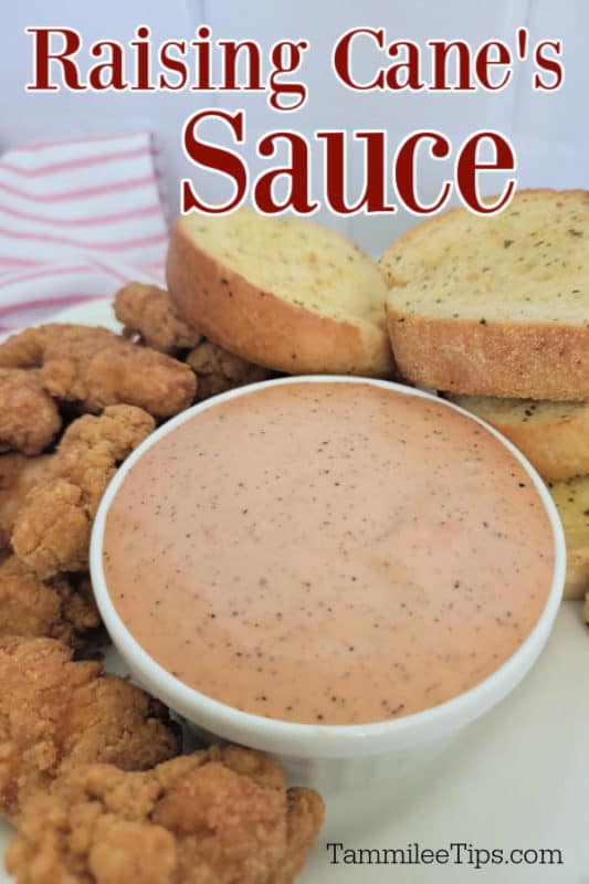 Raising Cane's Sauce over a bowl filled with sauce, garlic bread, and chicken pieces 