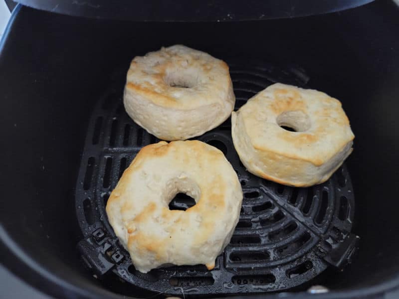 Three air fryer biscuit donuts in an air fryer basket