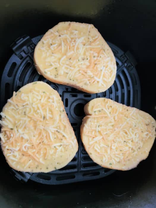 Three pieces of uncooked texas toast in the air fryer basket