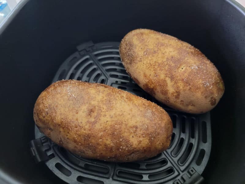 two potatoes in an air fryer basket