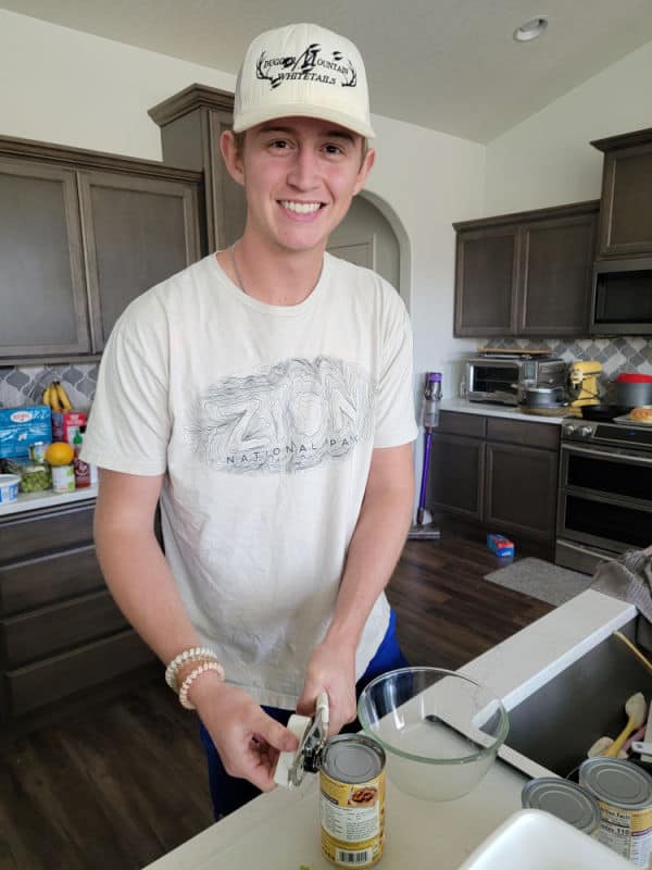 Young man opening a can of kidney beans in a kitchen