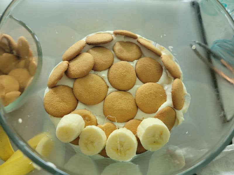Layers of nilla wafers and bananas to make Delicious Magnolia Bakery Banana Pudding Recipe in a glass trifle dish