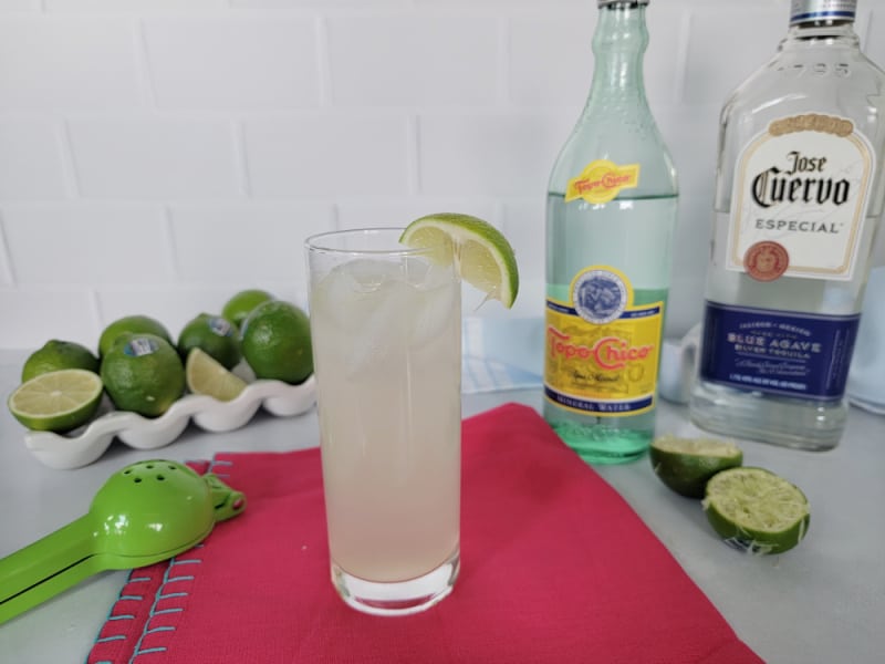 Ranch Water Cocktail in a highball glass on a red napkin with Jose Cuervo and Topo Chico and limes