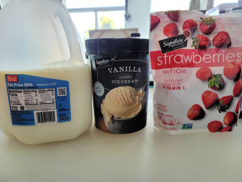 Strawberry milkshake ingredients, milk, vanilla ice cream, and frozen strawberries