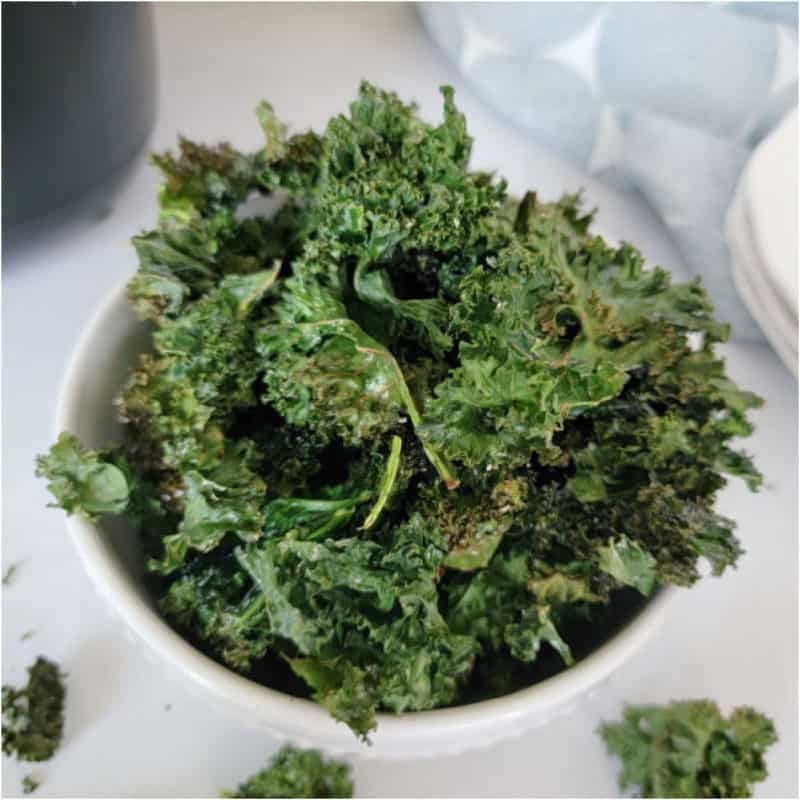 Air Fryer Kale Chips in a white bowl by a cloth napkin
