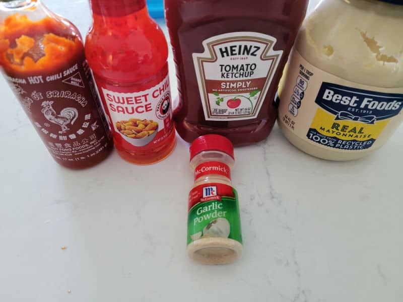Sriracha, sweet chili sauce, ketchup, mayo, and garlic powder on a white counter 