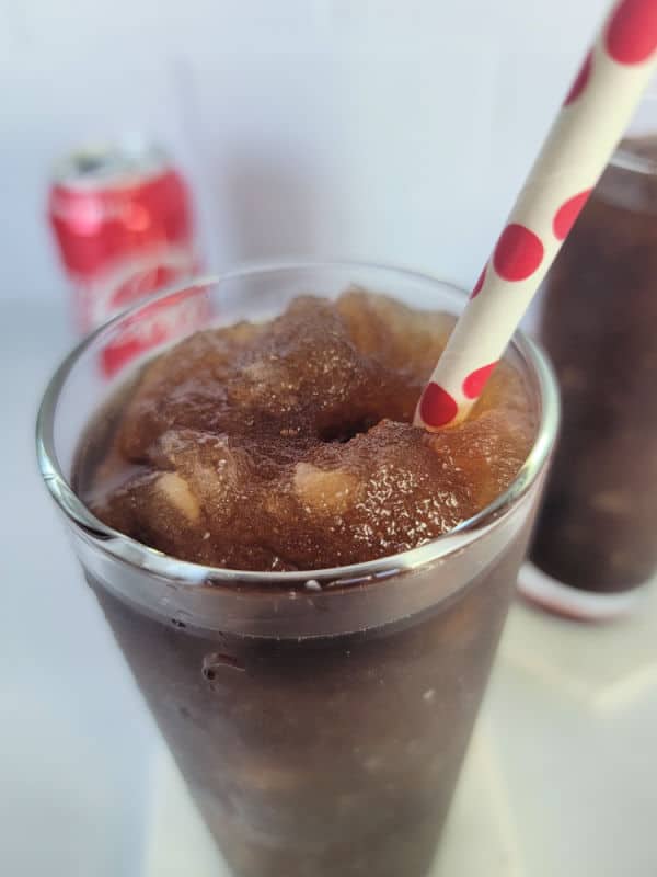 Close up of frozen coke in a tall glass with a red polka dot straw