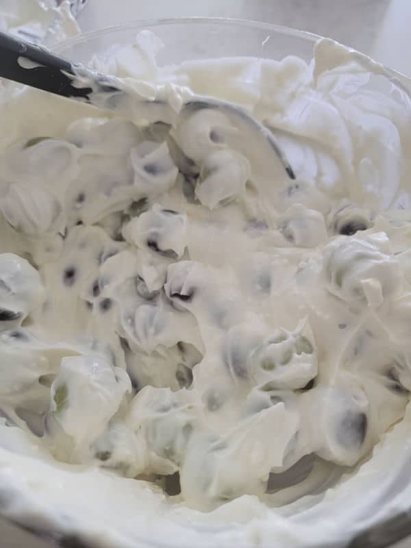 Grapes mixing with creamy dressing in a glass bowl 