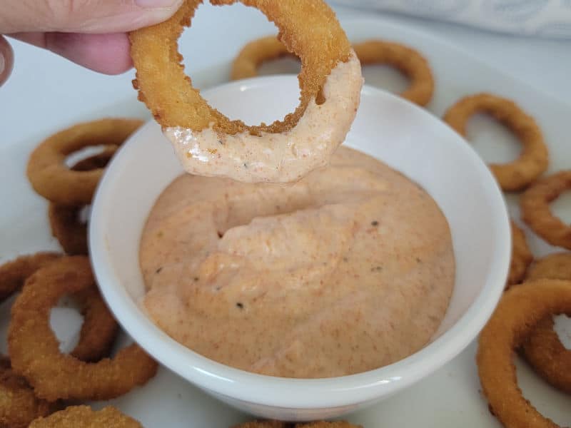 onion ring dipped in bloomin onion sauce in a white bowl 