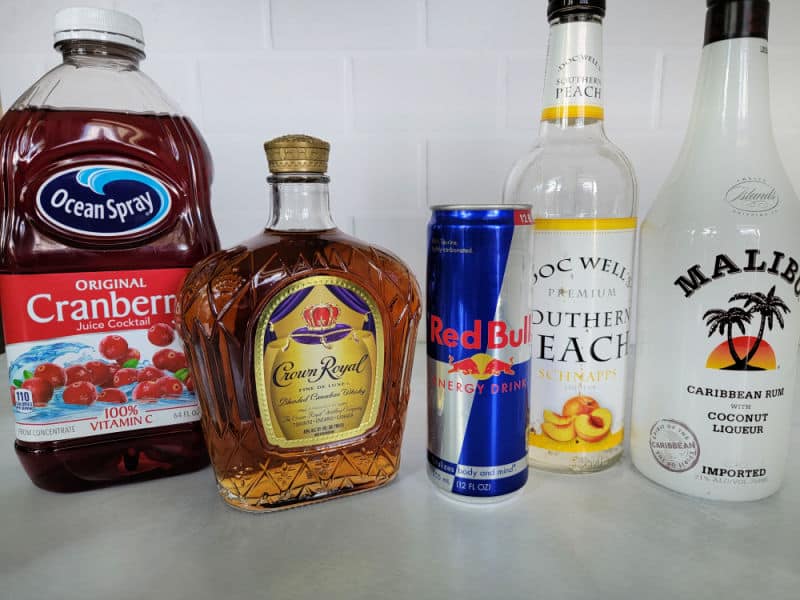 Cranberry juice, Crown Royal, Red Bull, Peach Schnapps, and a Malibu bottle on a counter