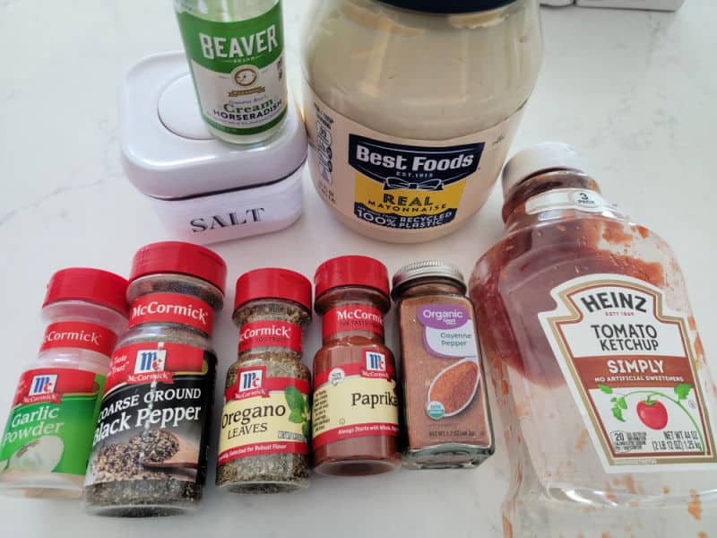 garlic powder, black pepper, oregano, paprika, cayenne pepper, ketchup, horseradish, onion and mayo on a white counter