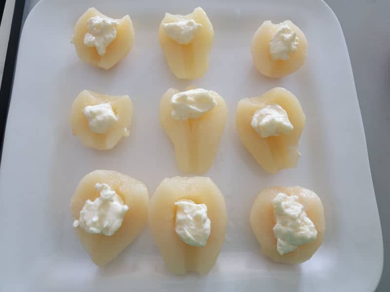 Pear halves with a dollop of mayo on them sitting on a white platter