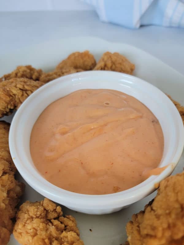Boom Boom sauce in a white bowl surrounded by chicken nuggets
