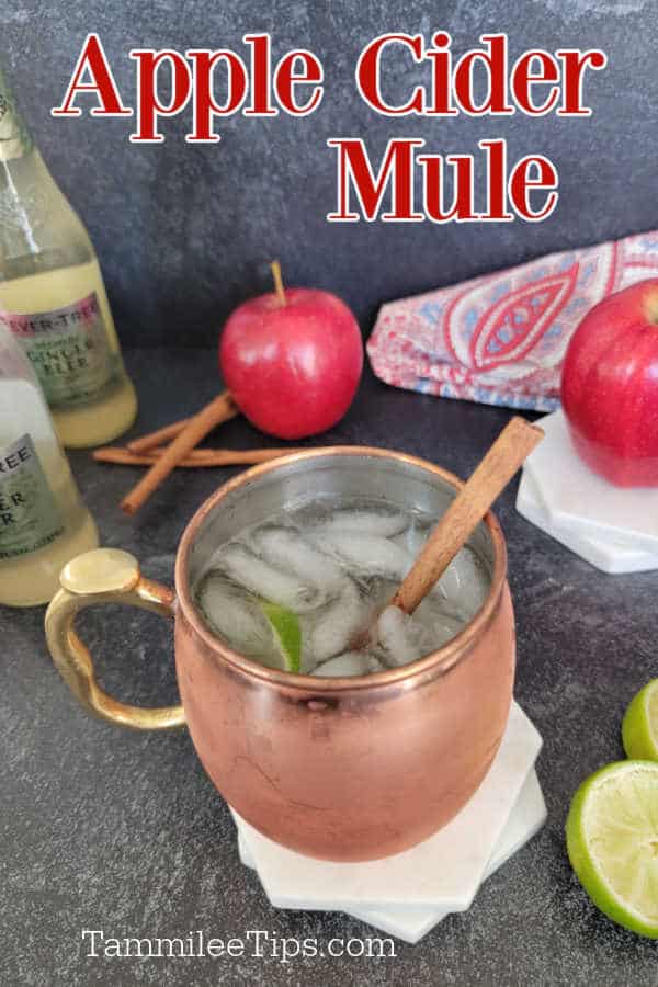 Apple cider mule text over a bottle of ginger beer, apples, cinnamon sticks, and an apple cider mule in a copper mug with ice