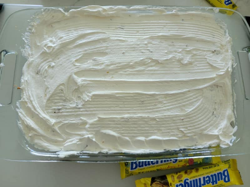 Cool whip spread over a chocolate poke cake for Butterfinger cake