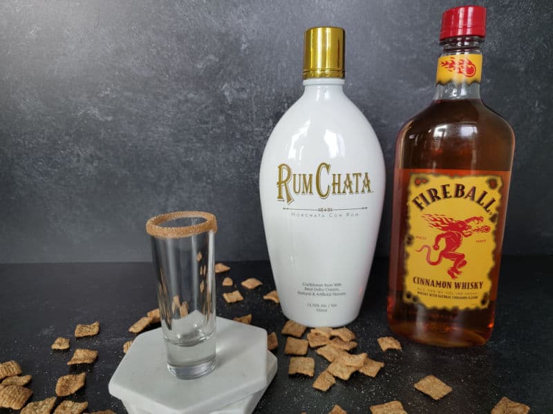 empty shot glass sitting on two marble coasters next to a bottle of Rumhcata and Fireball
