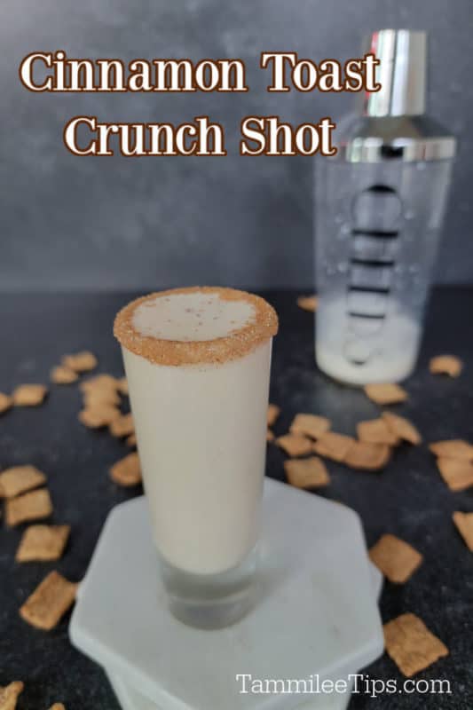 Cinnamon Toast Crunch Shot above a shot glass sitting on two marble coasters. Cocktail shaker in the background with cinnamon toast crunch cereal spread around it