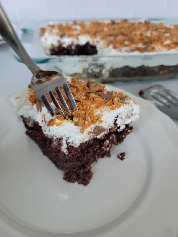 Fork going into a slice of Butterfinger Poke Cake