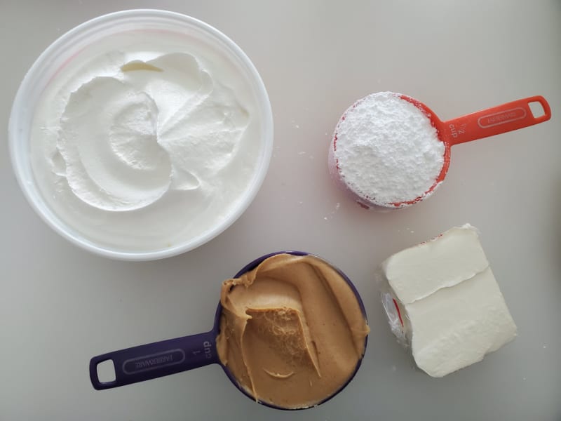 Cool whip, peanut butter, cream cheese, and powdered sugar on a counter