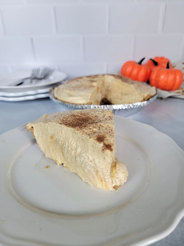 Slice of no bake pumpkin pie on a white plate with the pie dish in the background