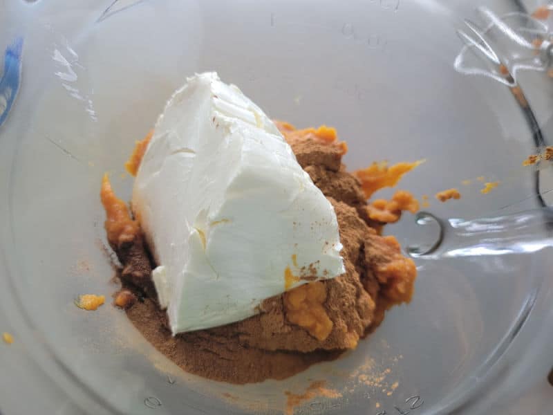 cream cheese and canned pumpkin in a glass batter bowl