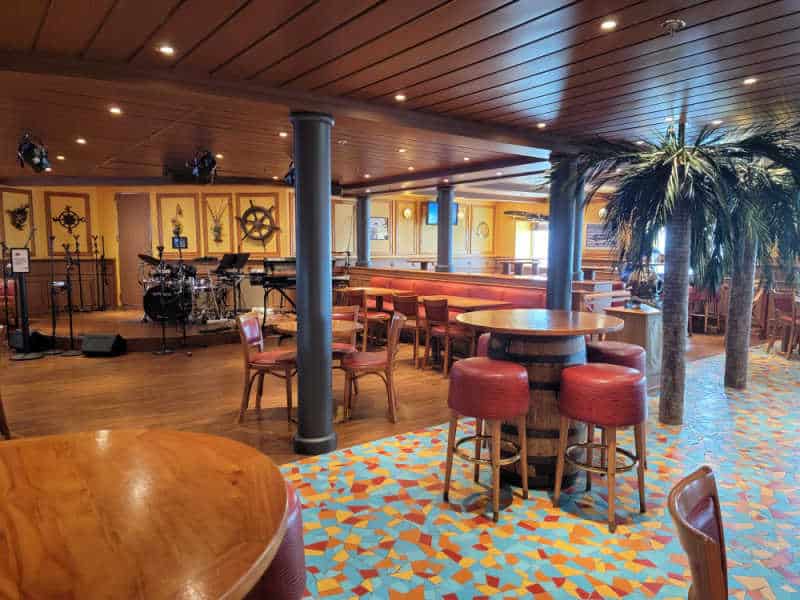 seating area in the Red Frog Pub on the Carnival Miracle with a band stage in the background. 