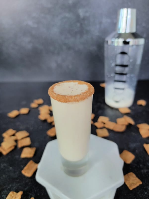 Cinnamon toast crunch shot on marble coasters with a cocktail shaker in the background