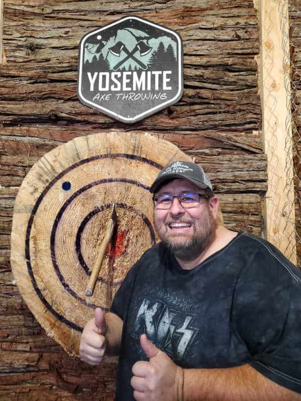Yosemite Axe Throwing sign and target with john standing in front of it