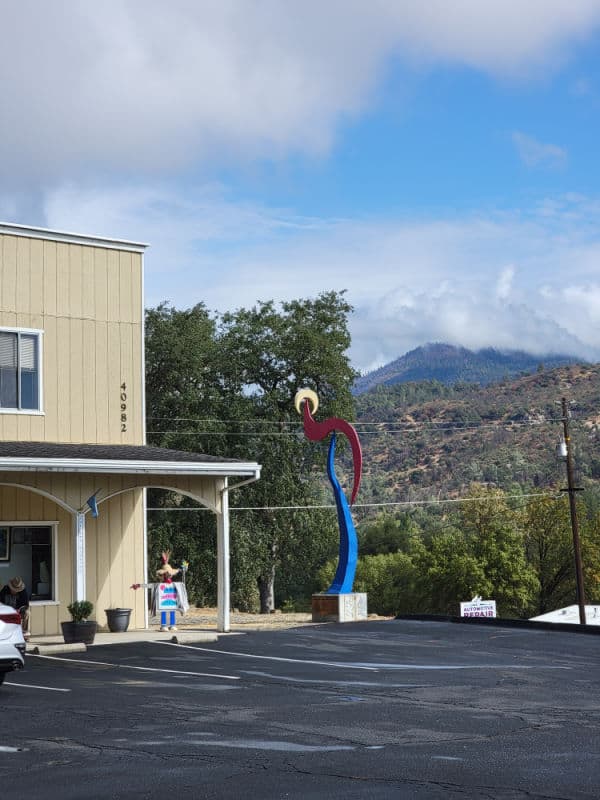 Art sculpture next to a brown building with mountains in the background