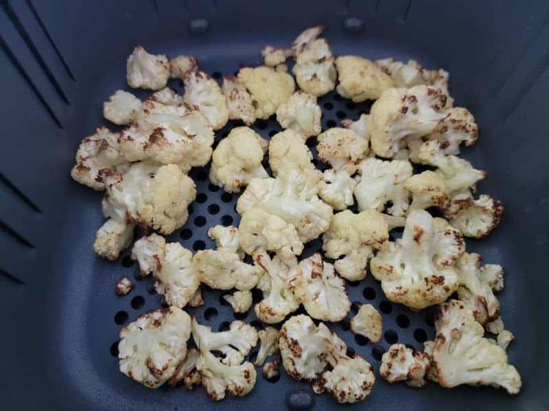 Air fried cauliflower florets in the air fryer basket 