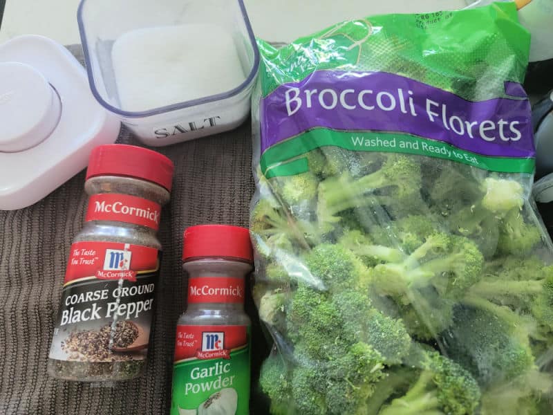 salt, pepper, and garlic powder next to broccoli florets in a bag