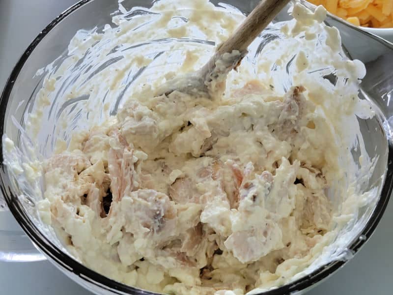 Shredded Chicken in a glass bowl being stirred with cream cheese mixture for Frank's Red Hot Buffalo Chicken Dip