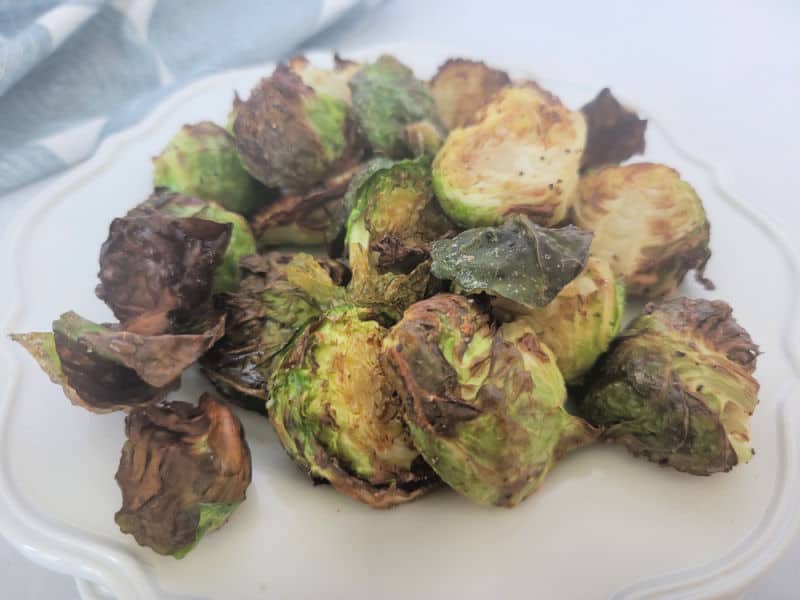 Air fried Brussel sprouts piled on a white plate near a napkin