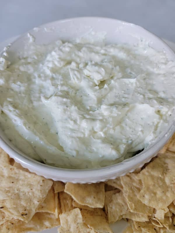 Ranch dip in a white bowl surrounded by tortilla chips