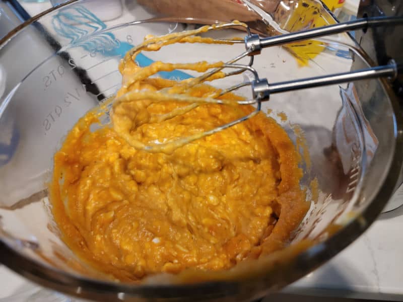 mixer beaters over a glass bowl with pumpkin in it