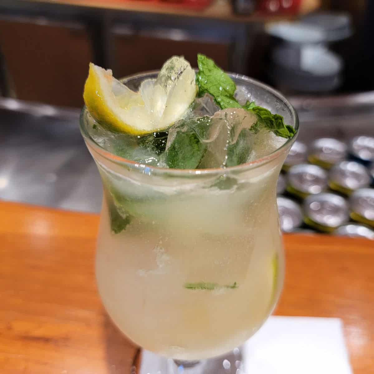 Ting Mojito in a hurricane glass with mint and lemon wedges