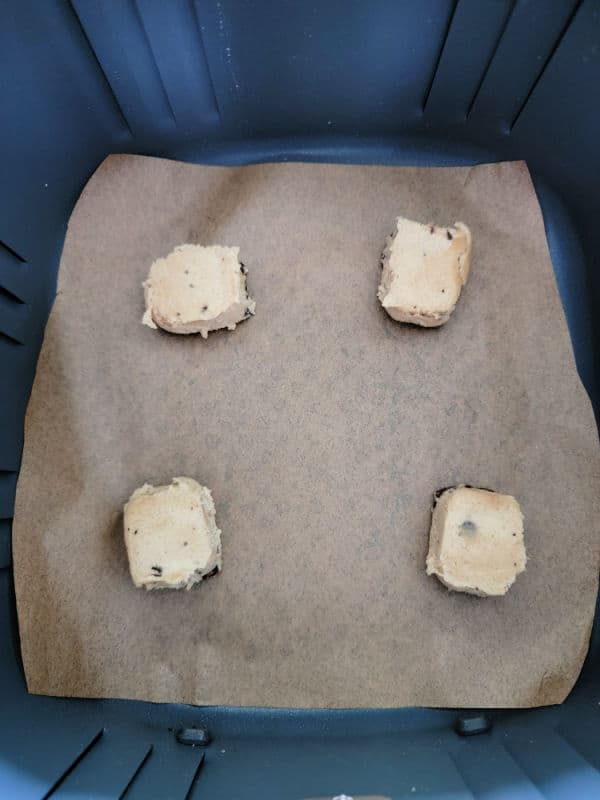Cookie dough squares on parchment paper in an air fryer basket