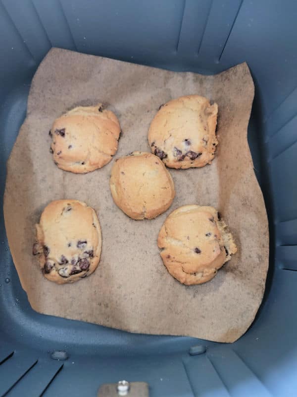 Chocolate chip cookies on parchment paper in an air fryer basket