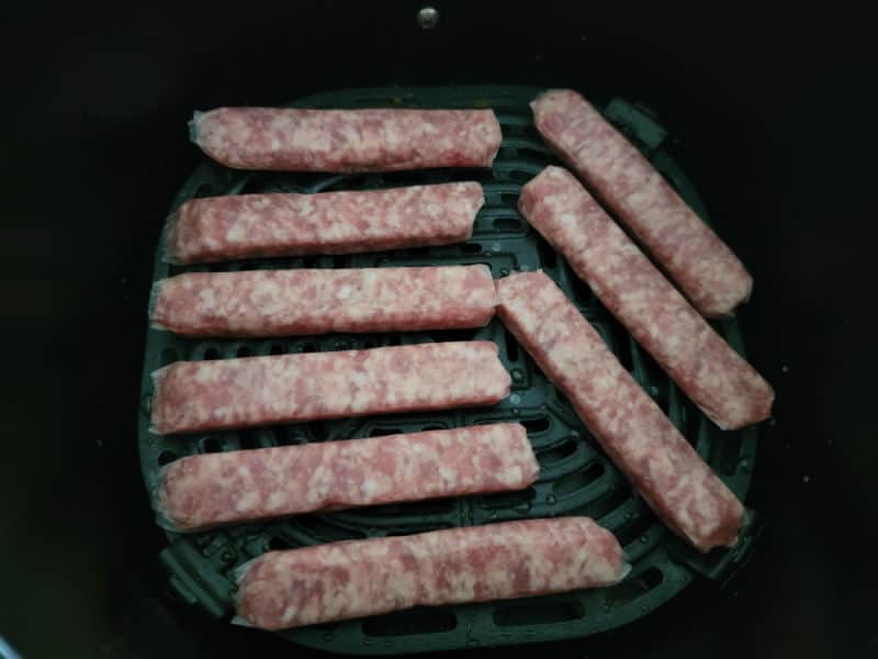 uncooked sausage links in an air fryer basket 