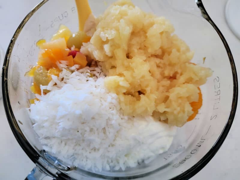 canned fruit mix, pineapple, and coconut in a glass mixing bowl 